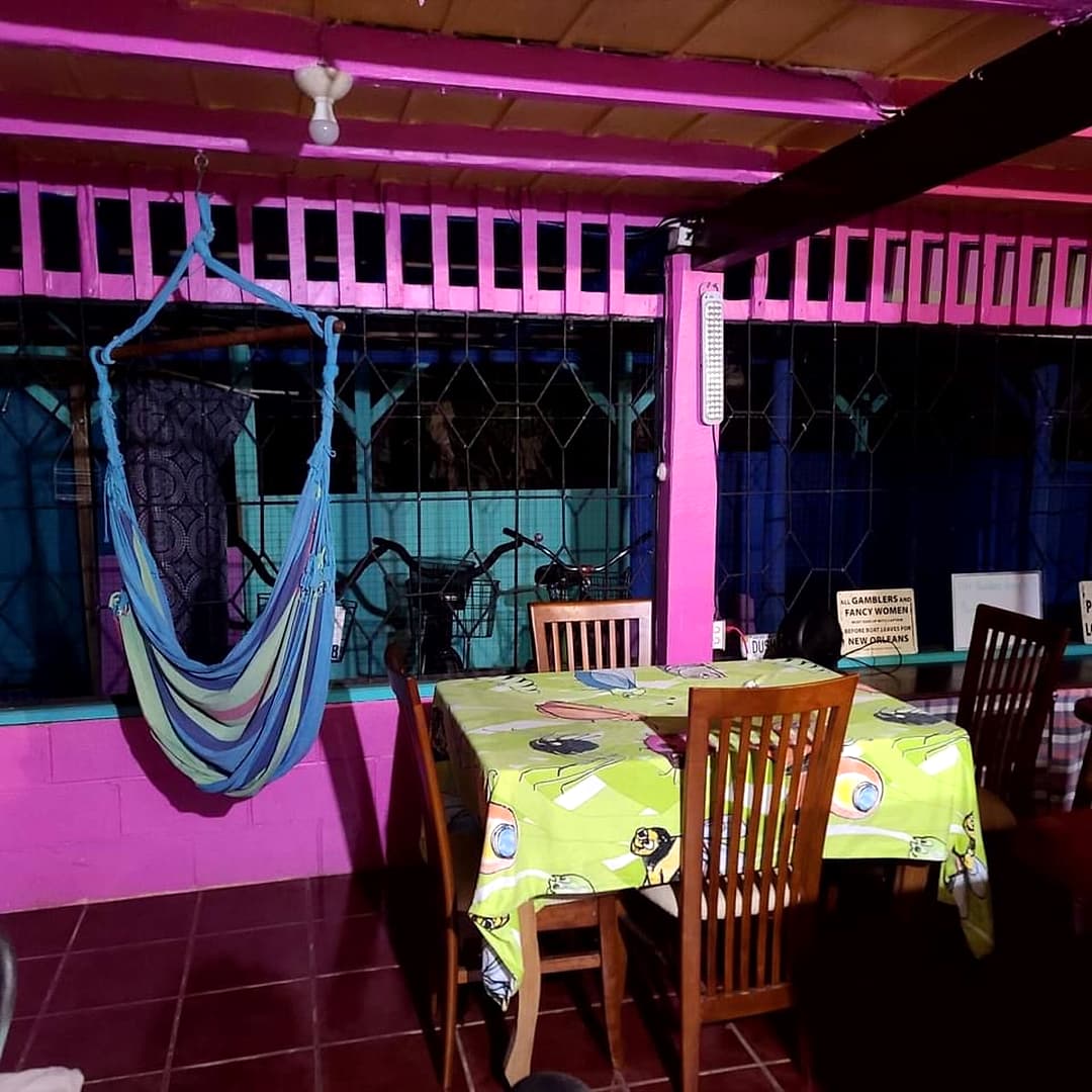 Pink-railed dining area with a hanging hammock chair and tables with yellow cloths
